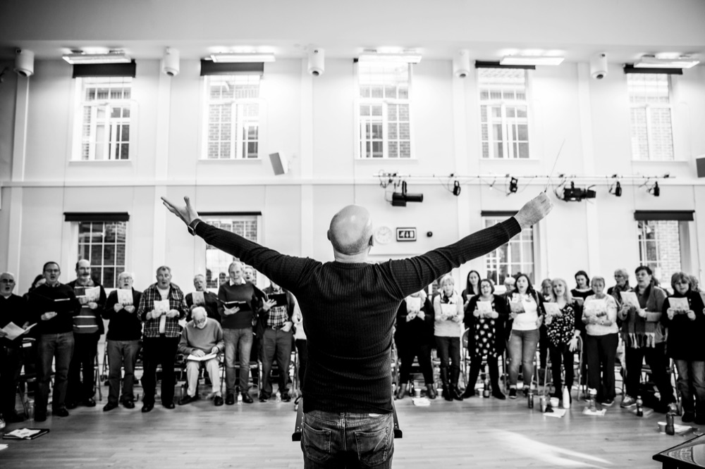 Russell Scott rehearsing with Next Stage Choir singers in a circle