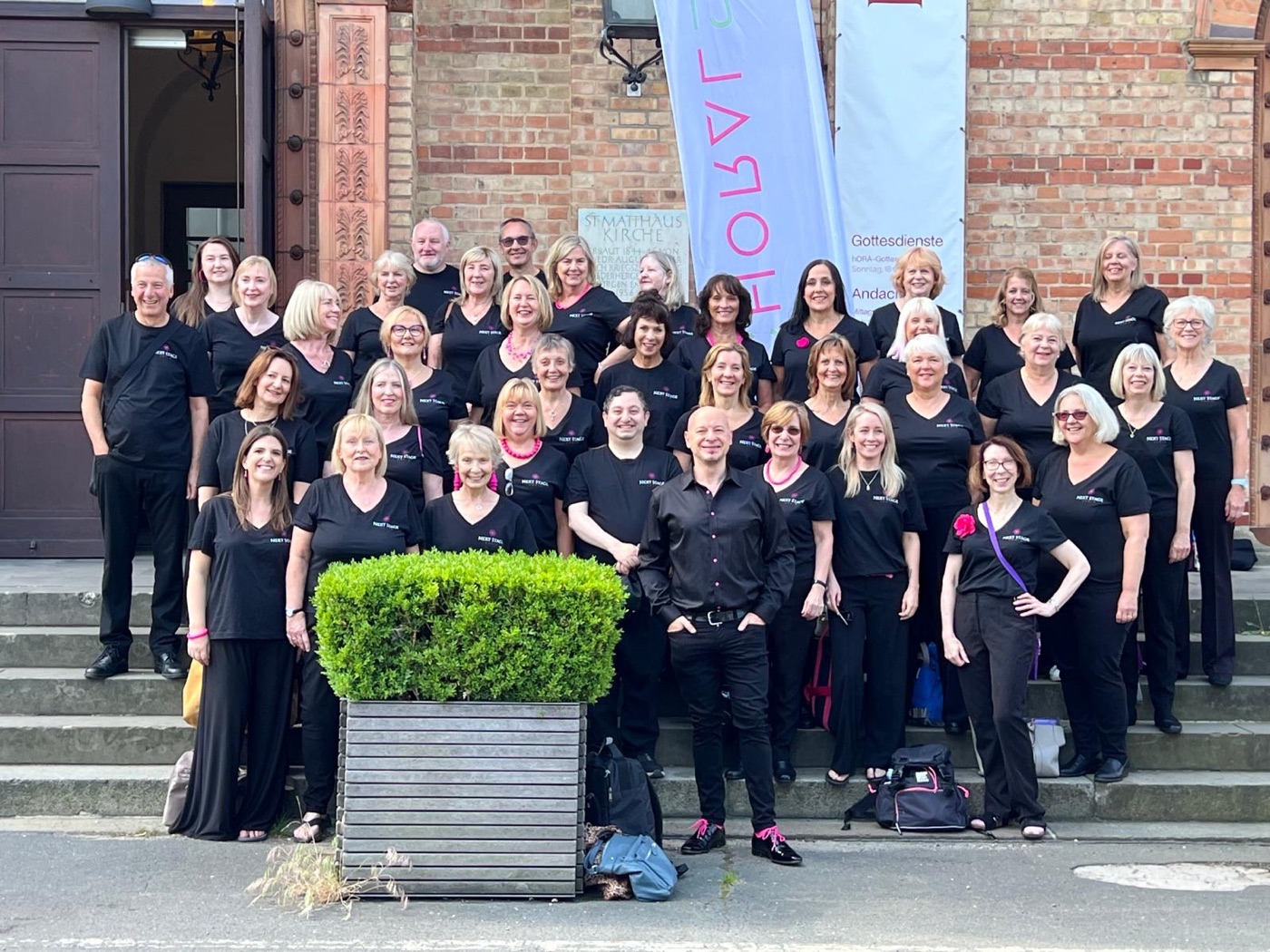 Next Stage Choir members smiling together outside a church